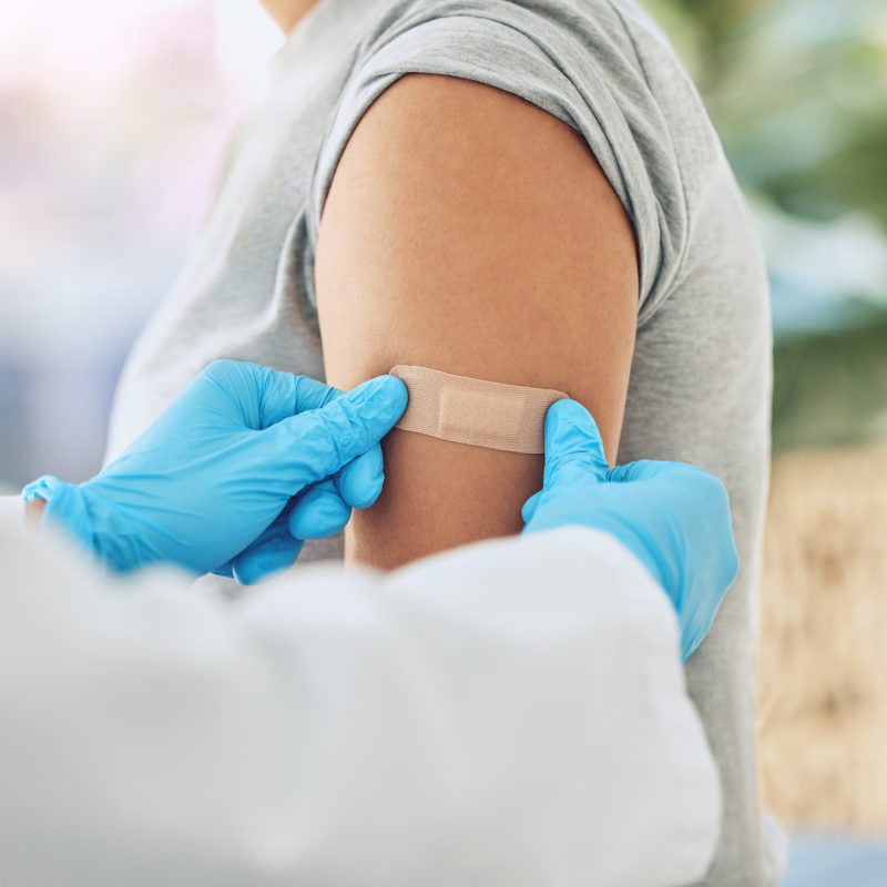 Covid virus vaccination, vaccine and doctor hands with plaster on patient arm in a medical hospital or clinic. Healthcare worker help, trust and safety flu shot antigen for protection against disease.