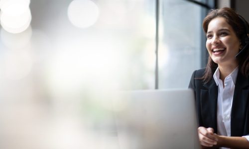 Attractive business woman Asian in suits and headsets are smiling while working with computer at office. Customer service assistant working in office. VOIP Helpdesk headset